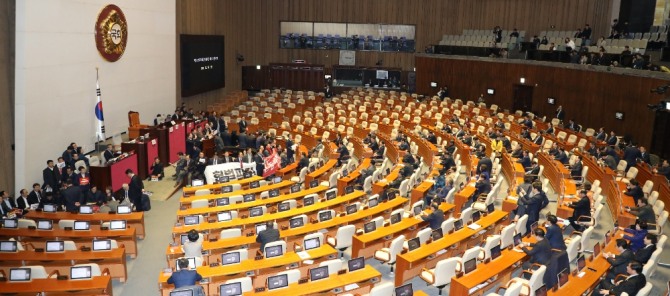 자유한국당 의원들이 지난 27일 오후 서울 여의도 국회에서 열린 제373회 국회 (임시회) 본회의에 처리를 앞둔 공직선거법 일부개정법률안을 막기위해 연단을 둘러싸 막고 있는 가운데 더불어민주당 의원들이 본회의장에 들어서 자리하고 있다. 사진=뉴시스
