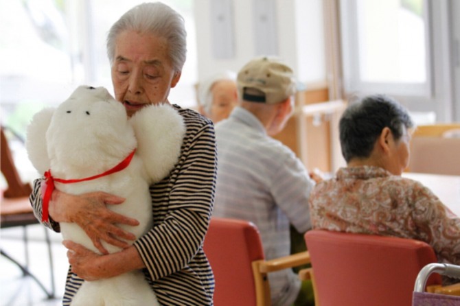 일본 후쿠시마현 이와키시 소재 요양시설에서 80대 노년 여성이 로봇 강아지를 안고 있다. 사진=로이터