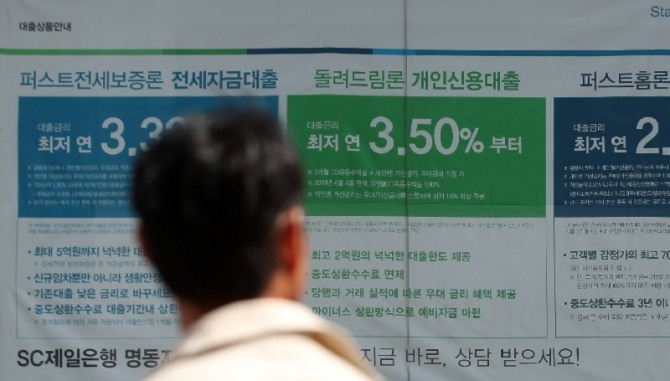 서울 시내의 한 은행 영업점에 붙은 대출 안내문을 길 가는 행인이 보고 있다. 사진=뉴시스 