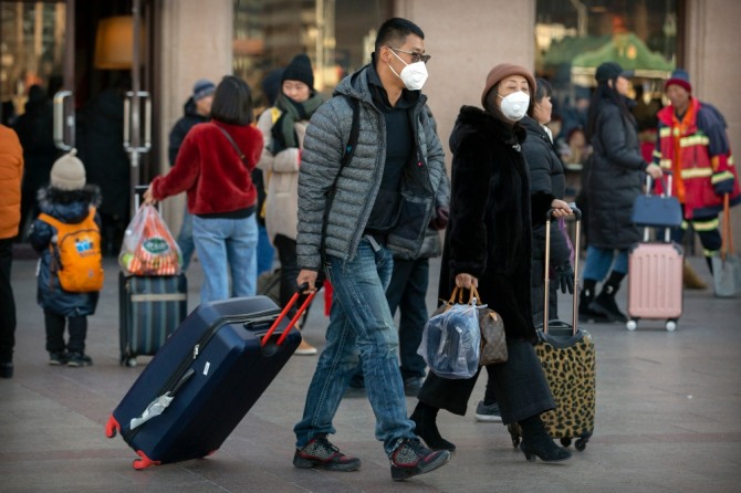 20일(현지시간) 중국 베이징의 베이징 철도역 앞에 여행객들이 마스크를 쓰고 이동하고 있다. 중국 정부는 우한 폐렴이 수도 베이징에서도 발생하면서 신종 코로나바이러스에 감염된 사람의 수가 급격히 늘고 있다고 발표했다. 특히 연휴를 맞아 수백만 명이 열차와 비행기를 이용하는, 중국에서 가장 인구 이동이 많은 시기와 겹쳐 대규모 확산이 우려되고 있다.  사진=뉴시스
