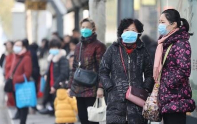 중국 후베이성 우한의 주민들이 20일 마스크를 쓴 채 신종 코로나바이러스에 의한 폐렴 발병 근원지로 지목돼 폐쇄된 해산물도매시장 인근 버스정류소에서 버스를 기다리고 있다.
