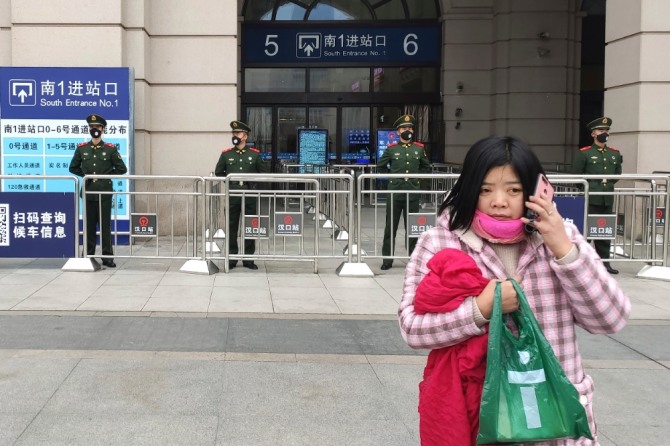 ‘우한 폐렴’이 강타한 중국 우한에서 지난 23일 봉쇄령으로 기차역이 폐쇄된 가운데 한 여성이 휴대전화통화를 하며 경찰들 앞을 지나가고 있다. 사진=뉴시스