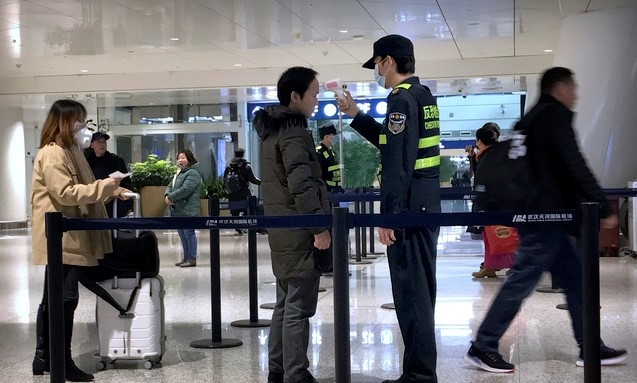 29일 중국 후베이성 우한시 국제공항에서 한 검역요원이 한 승객의 체온을 체크하고 있다. 우한발 폐렴이 전국 전역으로 확산돼 대유행 공포가 커지고 있다. (사진=뉴시스)