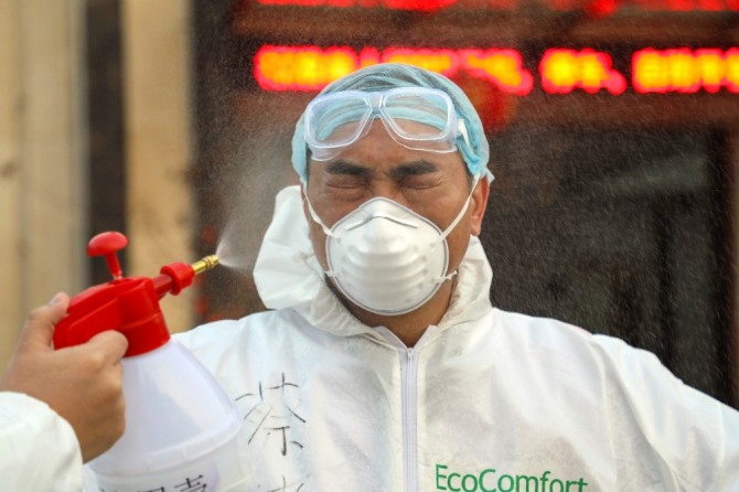 중국 후베이성 우한의 한 격리시설에서 3일 보호복을 입은 한 의료 요원이 소독약이 뿌려지는 동안 눈을 감고 있다. 우한의 의료진은 신종 코로나 사태로 격무와 감염 위험에 시달리고 있다. 사진=뉴시스