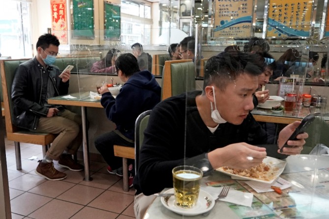 12일(현지시간) 홍콩의 한 식당에서 식당 손님들이 코로나19의 전파를 막기 위해 투명 플라스틱 칸막이가 설치된 식탁에서 식사하고 있다. 사진=뉴시스