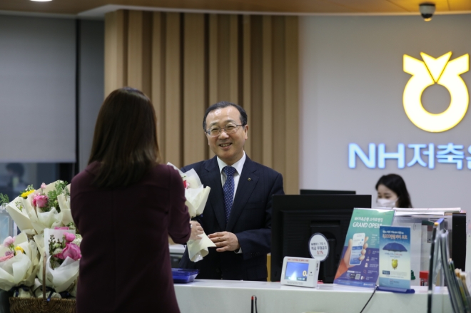 지난 14일 강남구  NH저축은행 본점영업부에서 김건영 대표이사(사진 가운데)가 영업점 고객에게 꽃을 나눠주고 있다. 사진= NH저축은행