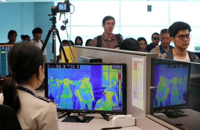 국립검역소 직원들이 17일 인천공항 2터미널에 도착한 내외국인 승객을 대상으로 발열체크 모니터를 통해 점검하고 있다. [사진=뉴시스]