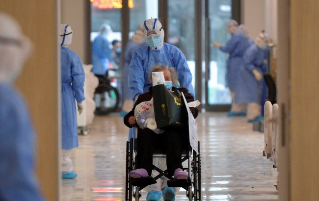 중국 후베이성 우한의 한 병원에서 보호 장비를 착용한 의료관계자가 신종코로나 환자의 휠체어를 밀고 있다. 