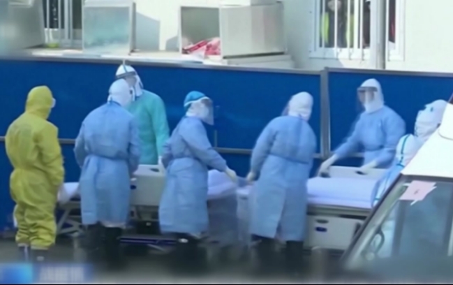 우한의 한 병원에서 방호복을 입은 의료관계자들이 코로나19 사망자의 시신을 옮기고 있다.