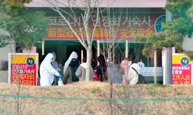 광주 호남대학교에서 입국한 중국 유학생들이 방호복을 입은 교직원의 안내를 받으며 임시 생활시설로 들어가고 있다. 사진=뉴시스
