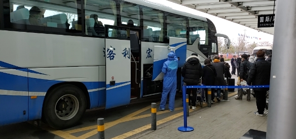중국 산둥성 웨이하이국제공항에서 25일 방역요원들이 제주항공편으로 입국한 승객들을 버스에 태우고 있다.사진=뉴시스,독자 제공