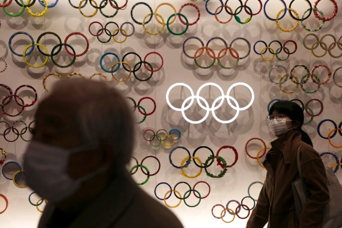 23일 마스크를 낀 시민들이 일본 도쿄의 올림픽 박물관을 지나고 있다. 신종 코로나바이러스 감염증(코로나19) 확산 속도가 높아지는 가운데 국제올림픽위원회(IOC)가 오는 7월 일본에서 개최 예정된 도쿄올림픽의 취소 가능성을 제기했다. 사진=뉴시스
