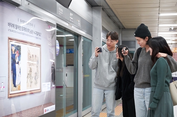 서울 지하철 6호선 공덕역 내 ’U+5G 갤러리’에 방문한 고객이 ‘U+AR’ 앱으로 작품을 체험하고 감상하고 있다. 사진=LG유플러스