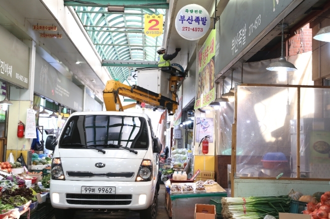 한국전력(한전) 관계자가 전통시장에서 노후조명설비를 교체하고 있다. 사진=한국전력 