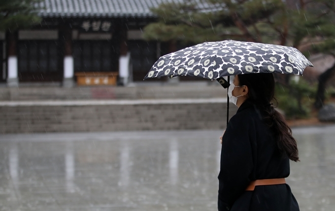 마스크를 착용한 한 여성이 비가 내리는 서울 서대문구 독립문 공원을 걸어가고 있다.   사진=뉴시스