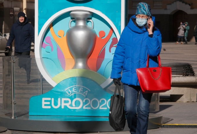 한 여성이 의료용 마스크를 쓴 채 유로 2020 엠블럼이 그려진 표지판을 지나가고 있다. 사진=뉴시스