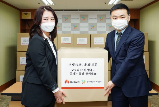 멍 샤오윈 한국화웨이 CEO(오른쪽)가 정은영 한국장애인복지시설협회 부회장에게  마스크를 전달한 후 기념사진을 찍고 있다. 사진=한국화웨이