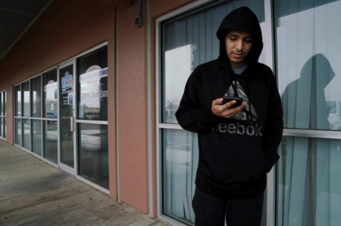 지난 20일(현지시간) 미국 텍사스주 러레이도에 있는 고용지원센터 앞에서 한 실직자가 스마트폰으로 취업정보를 살펴보고 있다. 사진=로이터