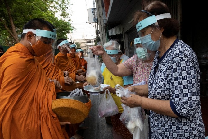 태국 방콕에서 신종 코로나바이러스 감염증을 예방하기 위해 마스크와 얼굴 가리개를 한 승려들이 시주를 받고 있다.  [AP/뉴시스]
