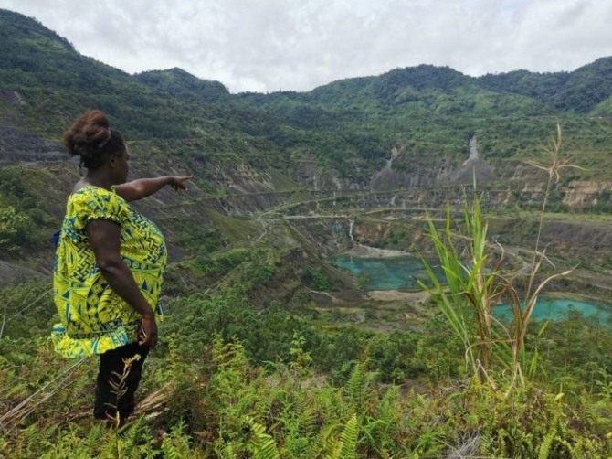 부겐빌에 거주하는 현지 여성이 파푸아뉴기니 판구나 광산을 가리키며 리오 틴토 기업의 20년 구리개발 사업이 부겐빌 지역의 수로를 오염시켰다고 설명했다. 사진=로이터