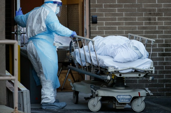  미국 뉴욕 브루클린의 와이코프 하이츠 병원에서 전신 보호복을 입은 의료 종사자가 신종 코로나바이러스 감염증(코로나19) 사망자 시신을 시체 안치소로 임시 사용하는 냉장 트레일러로 운반하고 있다. 사진=뉴시스