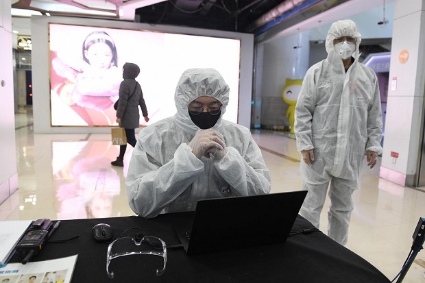 중국의 의료관계자들이 베이징 쇼핑몰 고객의 체온을 측정하기 전에 방호복을 입고 있는 모습. 