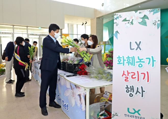한국국토정보공사(LX) 최규성 사장직무대행이 8일 전북 전주시 LX 본사 로비에서 개최한 화훼농가 살리기 행사에서 꽃을 구입하고 있다. 사진=LX 