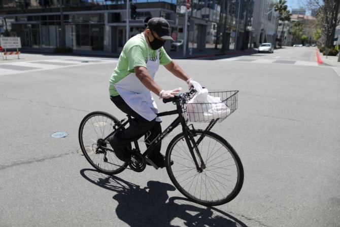 지난 15일(현지시간) 미국 로스앤젤레스 비벌리힐스의 한 음식점 직원이 자전거로 음식을 배달하고 있다. 사진=로이터