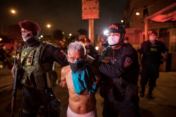 페루 수도 리마 외곽의 카야오에서 8일(현지시간) 경찰이 통행금지령을 어긴 남성을 체포, 연행하고 있다. AP/뉴시스 