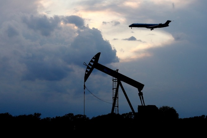 지난 21일(현지시간) 미 오클라호마주 오클라호마시티에 해가 지는 가운데 석유를 뽑아 올리는 '펌프잭' 위로 항공기 한 대가 착륙하고 있다. 사진=뉴시스