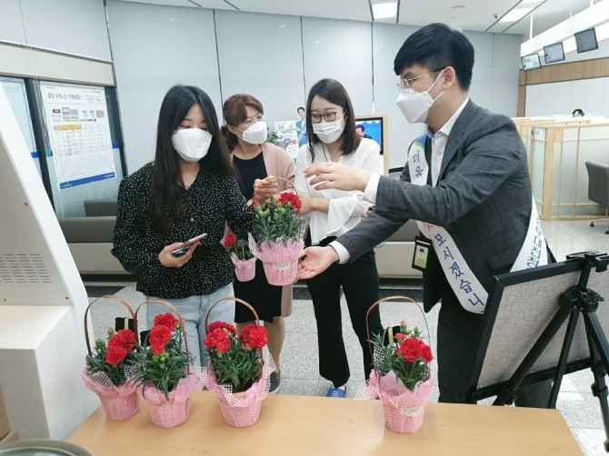 NH농협은행 정부대전청사지점 직원이 나눔행사에 방문한 고객에게 꽃을 전달하고 있다. 사진=NH농협은행