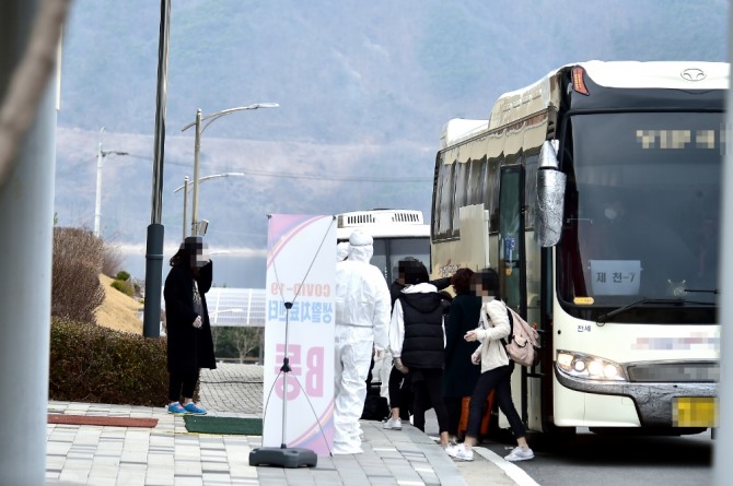 지난달 9일 수송버스에서 내린 코로나 경증환자들이 국민건강보험공단 인재개발원에 입소하고 있다.