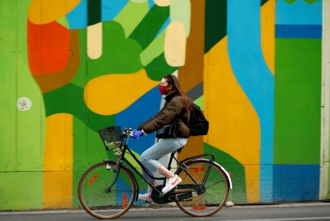 지난달 16일(현지시간) 벨기에 브뤼셀 시내에서 한 여성이 마스크를 쓴 채 자전거로 이동을 하고 있다. 사진=로이터