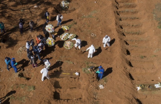 브라질 상파울루주의 빌라포르모사 공동묘지에서 보호장구를 착용한 관계자들이 코로나19로 사망한 희생자의 관을 묻고 있다.