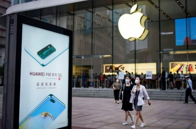 마스크를 쓴 중국여성들이 상하이 애플매장앞 화웨이광고탑 옆을 지나가고 있다. 사진=로이터