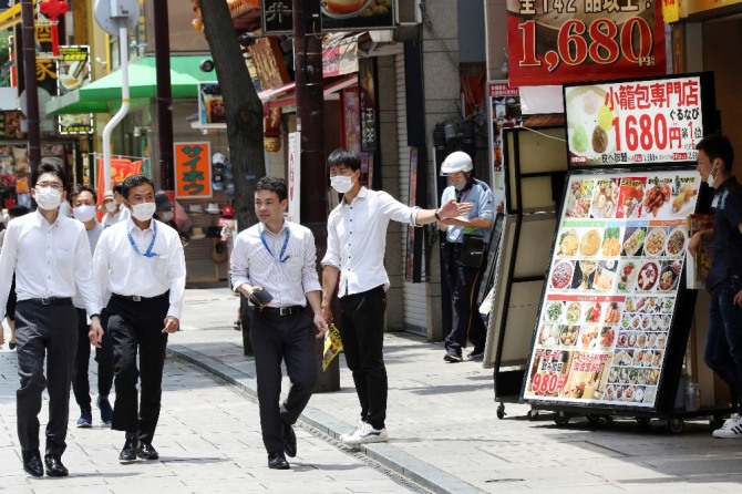 3일 일본 도쿄 인근 요코하마 차이나타운에서 마스크를 쓴 식장 직원이 호객행위를 하고 있다. AP/뉴시스
