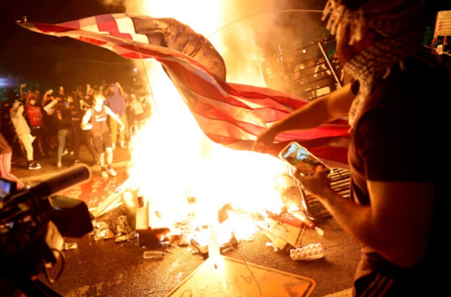 미국 워싱턴 DC에서 조지 플로이드 사망사건에 항의하는 시위대가 피워 놓은 불구덩이에 성조기를 태우고 있다. 
