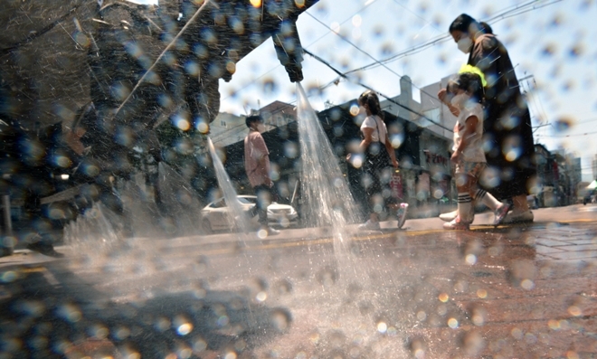 대구시 중구청 관계자들이 7일 폭염으로 뜨거워진 거리에 물을 뿌려 도로 열기를 식히자 어린아이들이 물장난을 치며 즐거운 시간을 보내고 있다. 사진=뉴시스