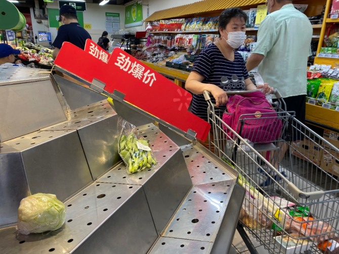 최근 중국 베이징의 농수산물 도매시장에서 신종 코로나바이러스 감염증(코로나19) 집단 발병 여파가 최소 3개 성으로 확산한 가운데 15일(현지시간) 마스크를 쓴 한 여성이 베이징의 한 슈퍼마켓 텅 빈 야채 판매대 앞을 지나고 있다. 사진=뉴시스