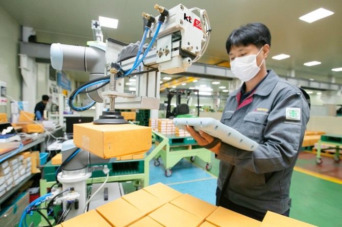 한 생산직 근로자가 충북 제천에 있는 박원 공장에서 KT 5G 스마트팩토리 코봇과 함께 작업하고 있다. 사진=KT