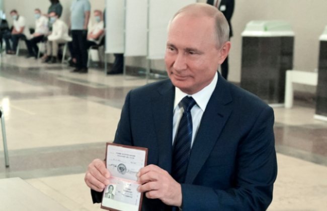 블라디미르 푸틴 러시아 대통령이 1일(현지시간) 러시아 모스크바의 한 투표소에 도착해 신원 확인을 위해 선거관리위원회 관계자에게 여권을 보여주고 있다.