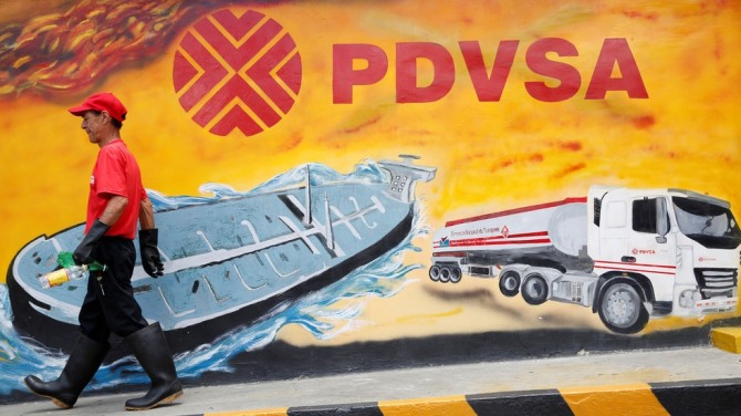 베네수엘라 국영 석유회사 PVDSA  선전 입간판 앞을 베네엘라 국민이 지나고 있다. 사진=로이터