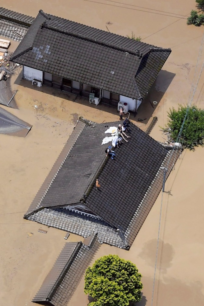4일 일본 규슈지역 구마모토(熊本)현 히토요시(人吉)시에서 폭우로 가옥이 물에 잠기자 주민들이 지붕 위에 올라가 구조를 기다리고 있다. AP/뉴시스