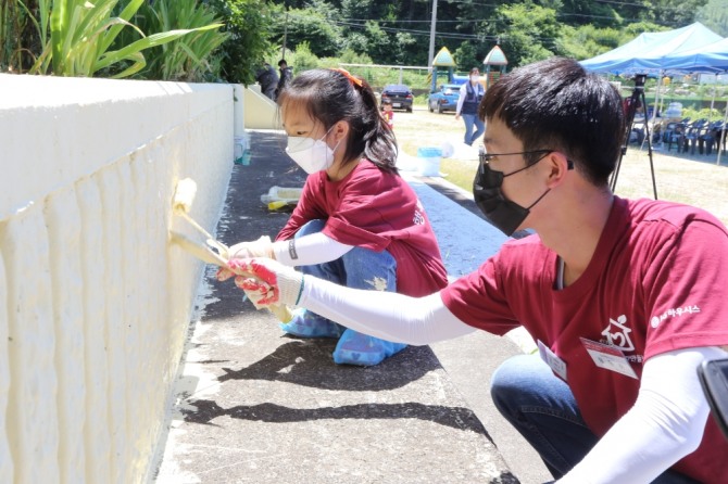 '행복한 공간 만들기'에 참여한 LG하우시스 직원과 자녀가 학교 외벽을 꾸미고 있다. 사진=LG하우시스