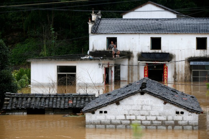 안후이성 황산에 폭우가 쏟아지자 사람들이 망연자실한 채 물에 잠긴 마을의 집을 바라보고 있다. 사진=로이터