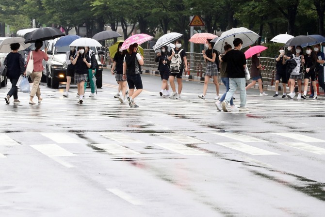학생들이 우산을 쓰고 도로를 건너가고 있다. 사진=뉴시스