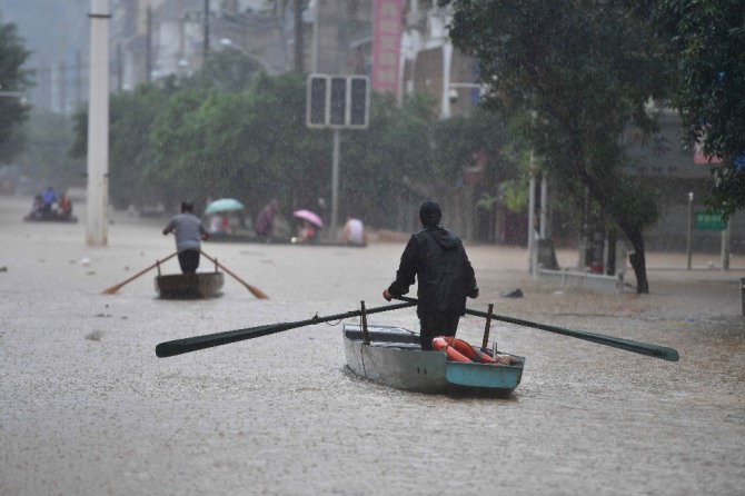 중국에서 홍수가 계속되는 가운데 12일 광시 좡족 자치구에서 물로 가득 찬 거리를 사람들이 배를 타고 건너고 있다. AP/뉴시스