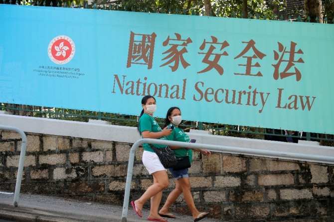 홍콩의 여성들이 홍콩 국가보안법 홍보 현수막 앞을 지나고 있다. AP/뉴시스