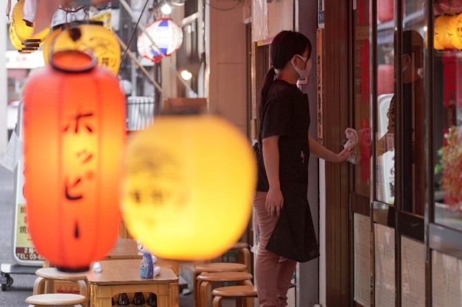 20일 일본 도쿄의 한 음식점에서 마스크를 쓴 직원이 창문을 닦고 있다.  AP/뉴시스