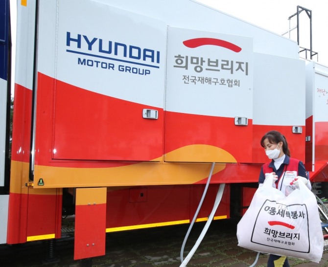 전국재해구호협회 자원봉사자가 최근 폭우로 물난리를 겪은 경북 영덕군 강구시장을 찾아 현대자동차그룹 이동 세탁 차량으로 세탁물을 나르고 있다. 사진=현대차그룹